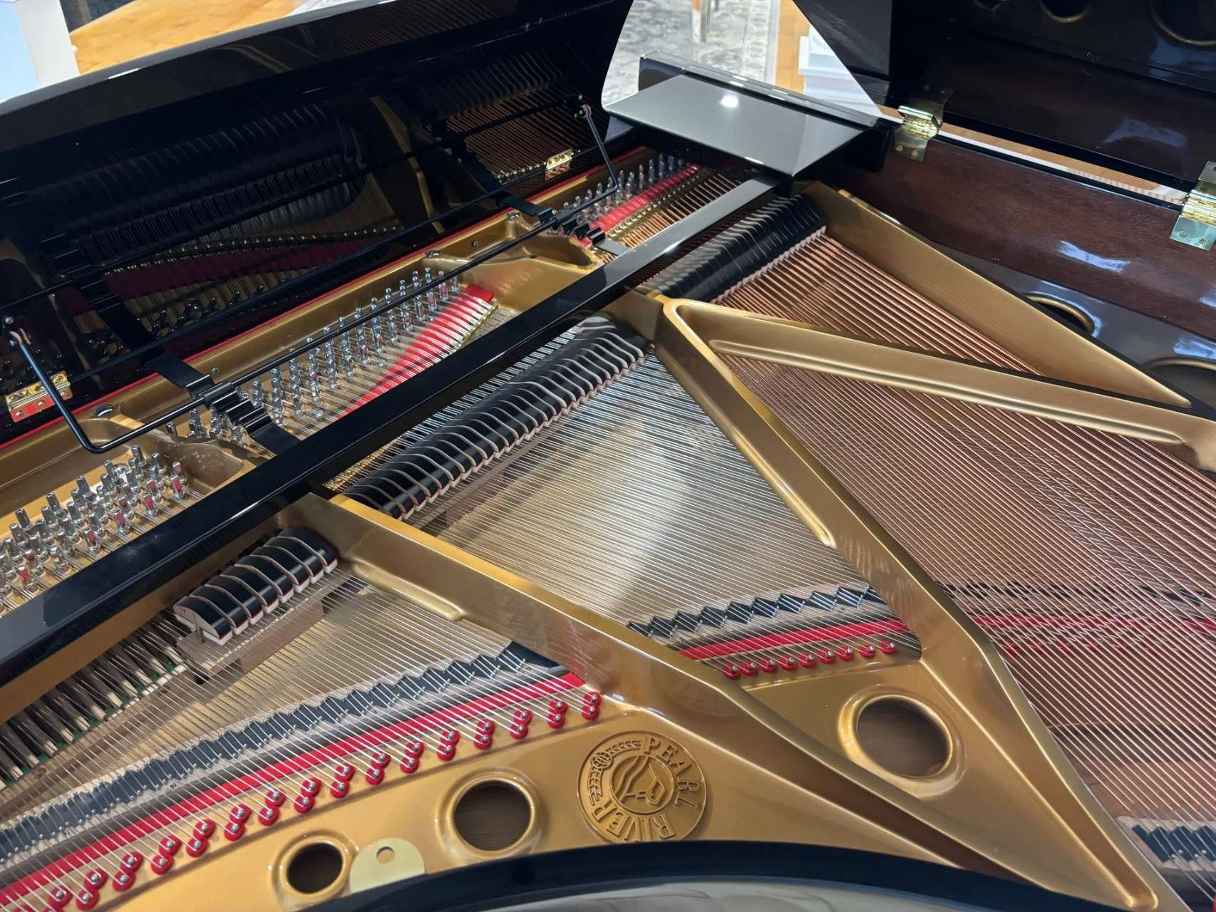 Detailed view of Pearl River grand piano strings and soundboard condition