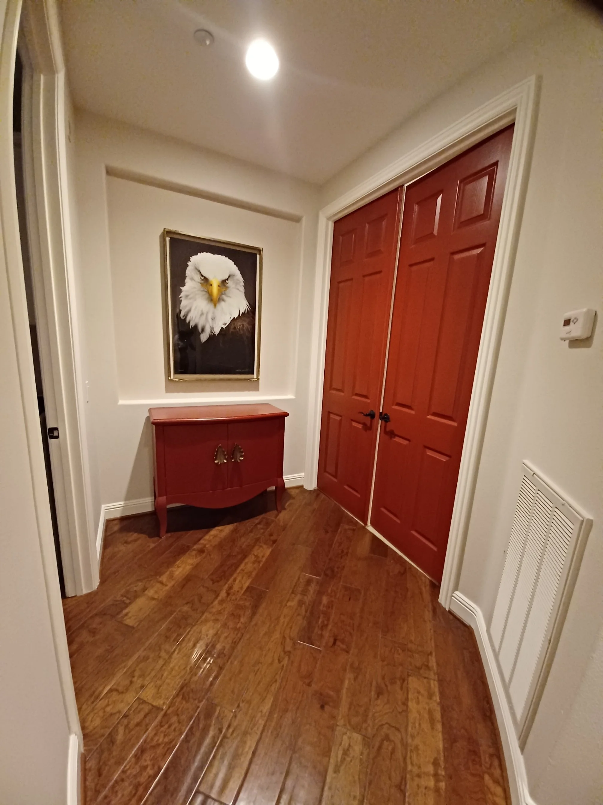 Entryway with a red console table, and a double wooden entry door.