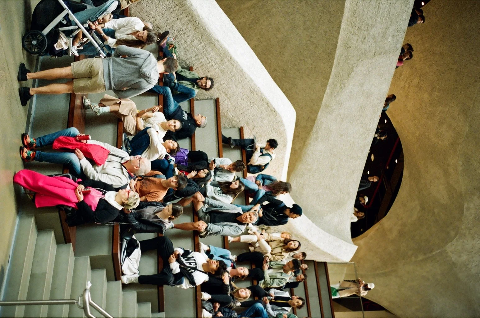 Overhead analog film photograph of a diverse crowd seated on museum stairs in New York City, shot by film street photographer Dario Tapia.