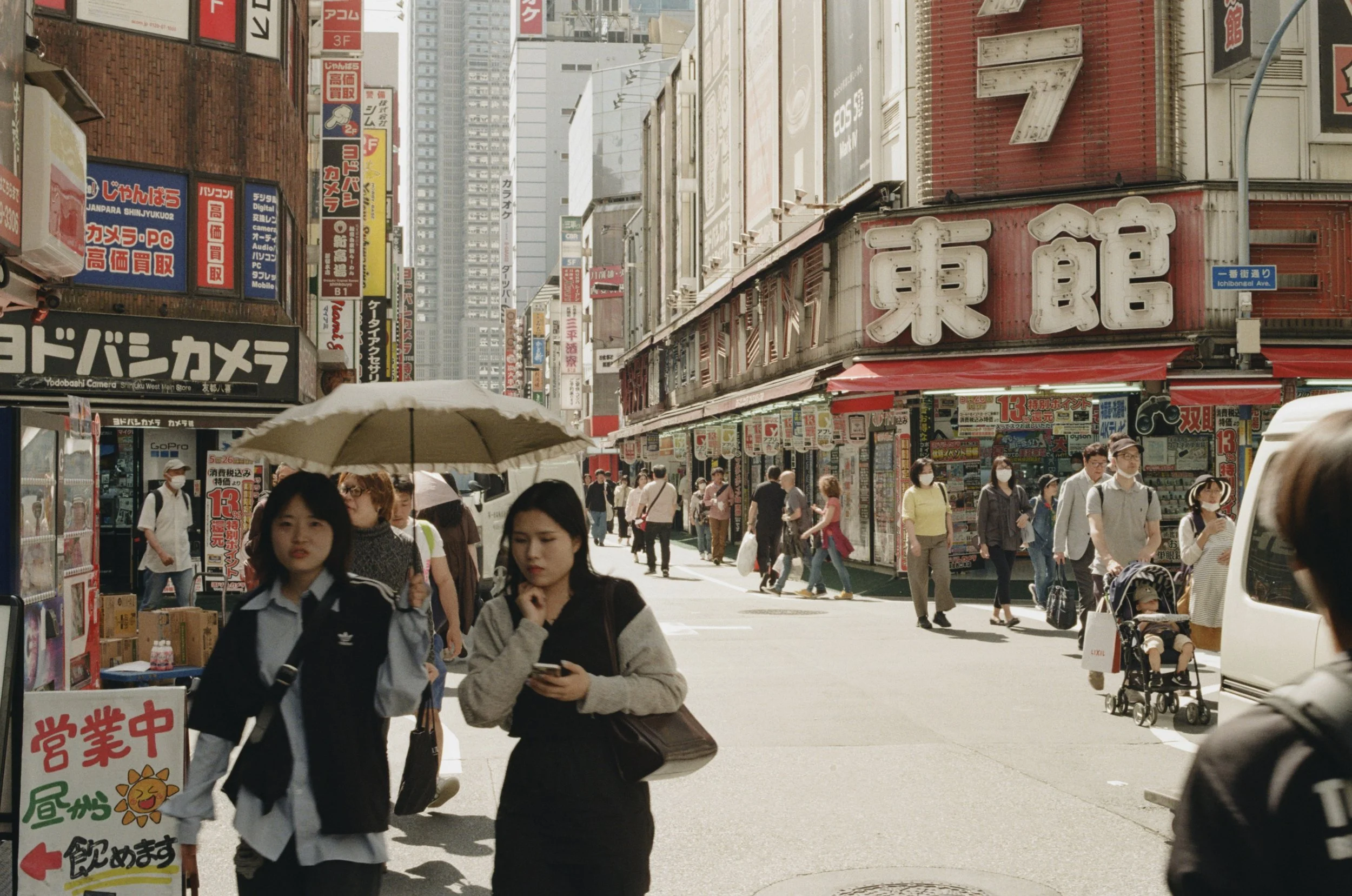 Candid film street photography of Shinjuku, Tokyo — busy urban street scene with pedestrians, neon signage, and natural light. Shot on film by Dario Tapia, NYC-based street photographer.