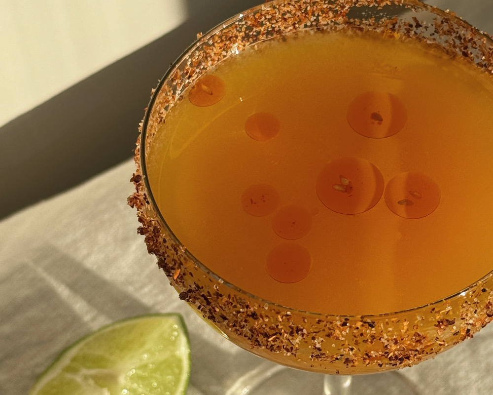  Closeup of spicy mandarin margarita with drops of chilli oil floating on the surface 