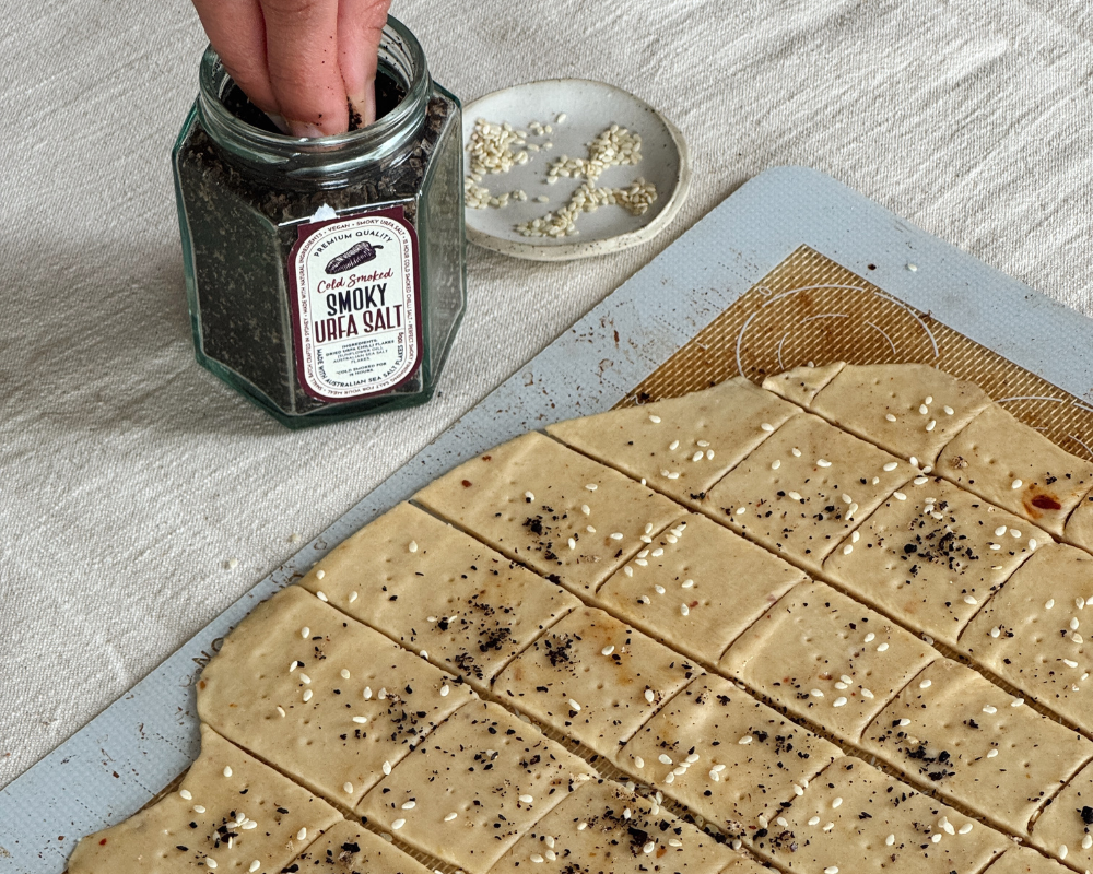  A baking mat with homemade crackers ready to be baked and a jar of smoked salt 