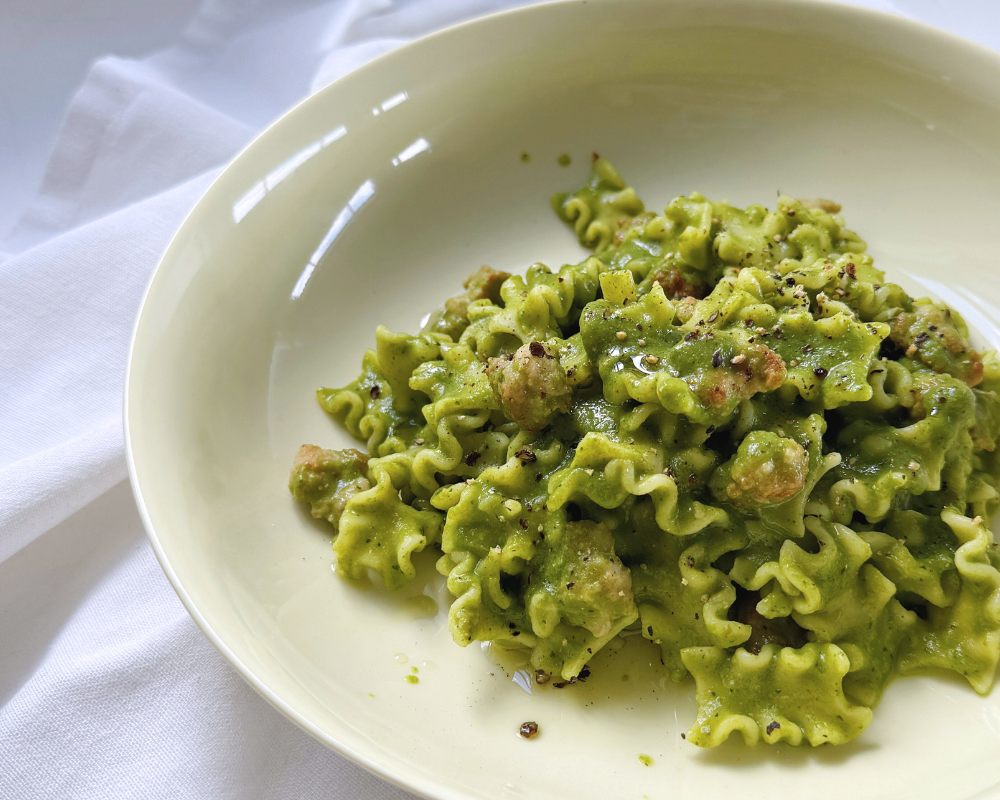  Closeup of yellow bowl against a white background with a green pasta in it 