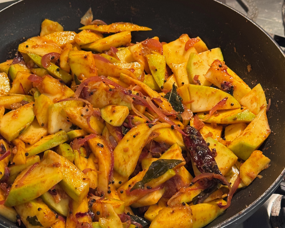 Raw mangoes in pan being fried.png