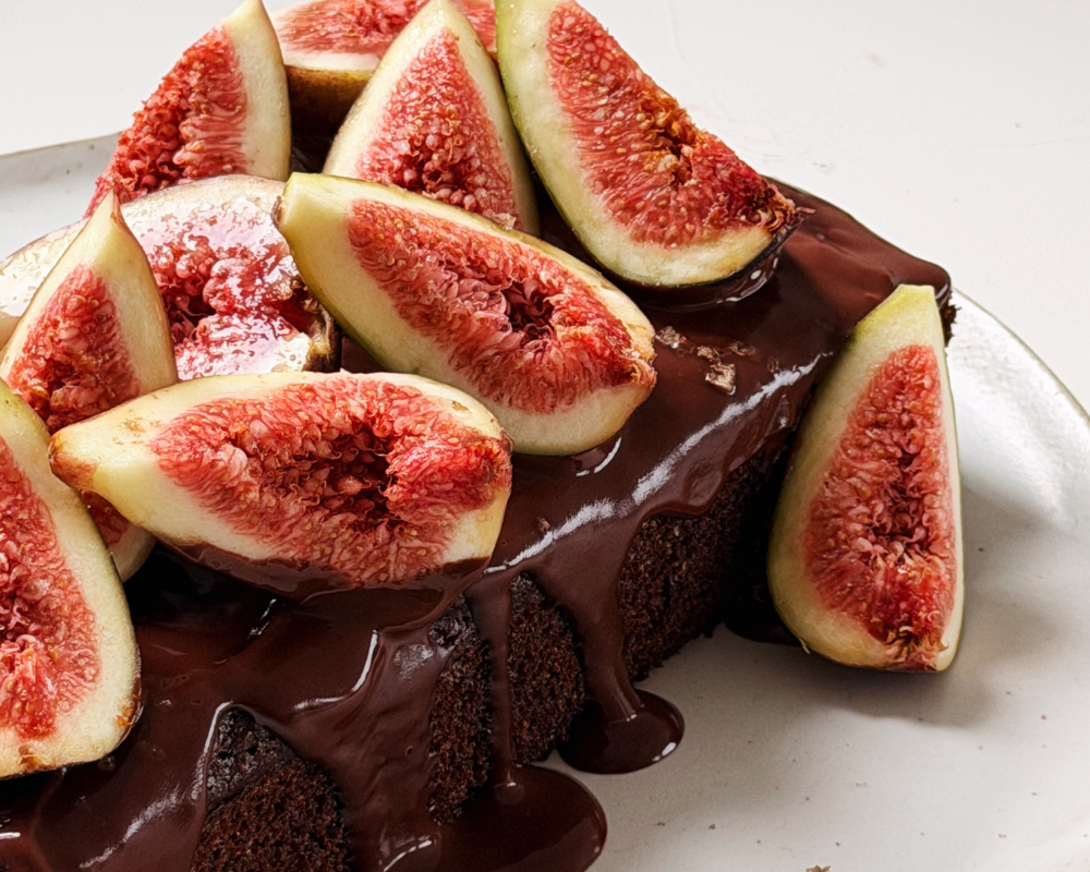  Close up of fresh fig slices piled on top of a chocolate cake with dark chocolate ganache drizzle 