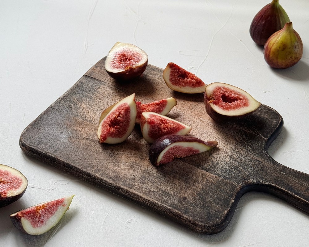  Fresh figs sliced into quarters on a dark wooden chopping board 