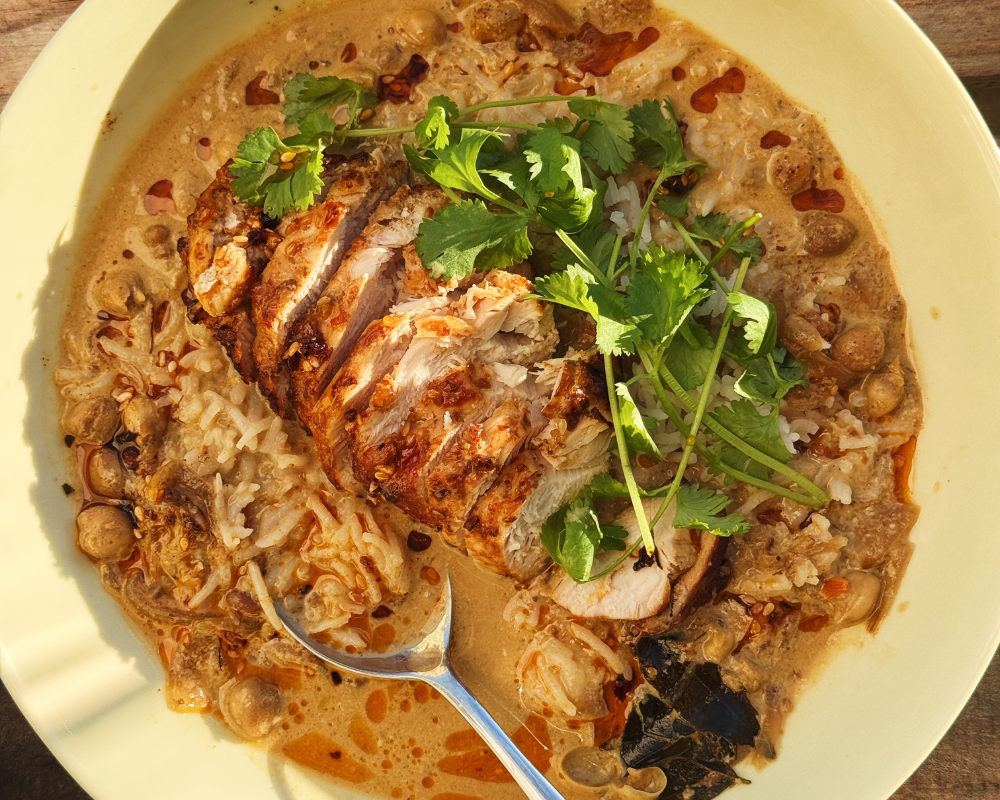  A close up of brothy coconut curry and rice with chicken 