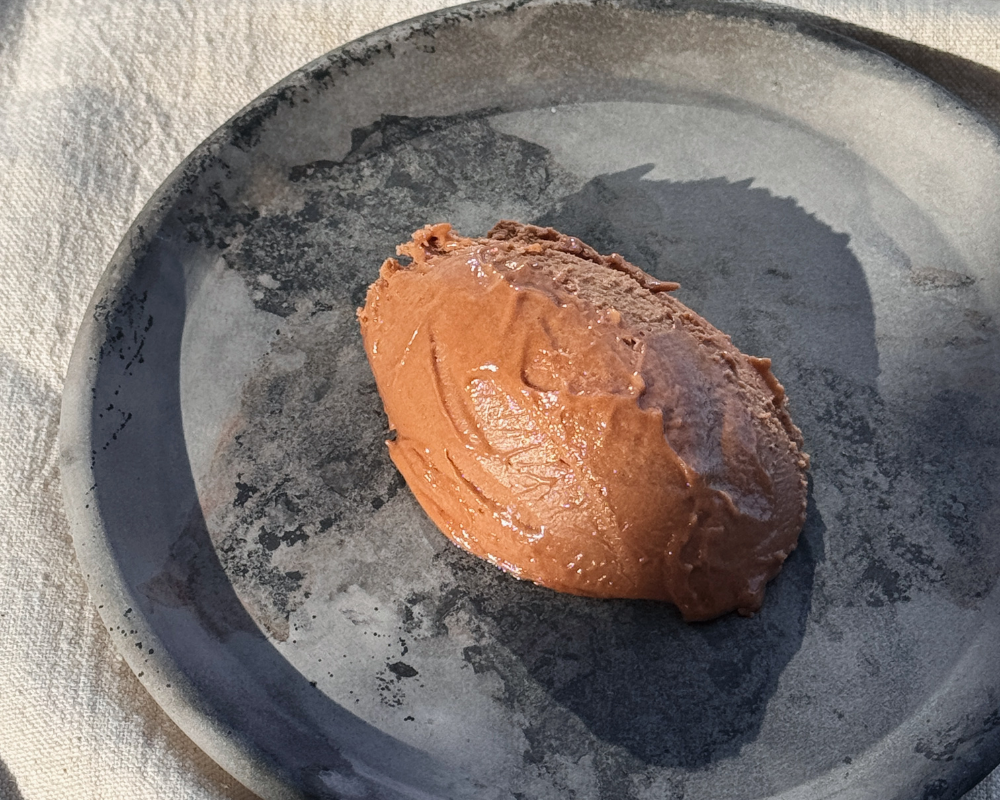  A quenelle of hazelnut chocolate mousse served on a dark grey ceramic plate 