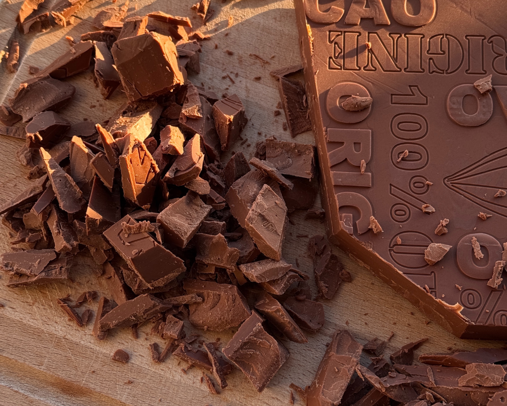  Chopped Cuvée Gianduja chocolate bar on a wooden cutting board 