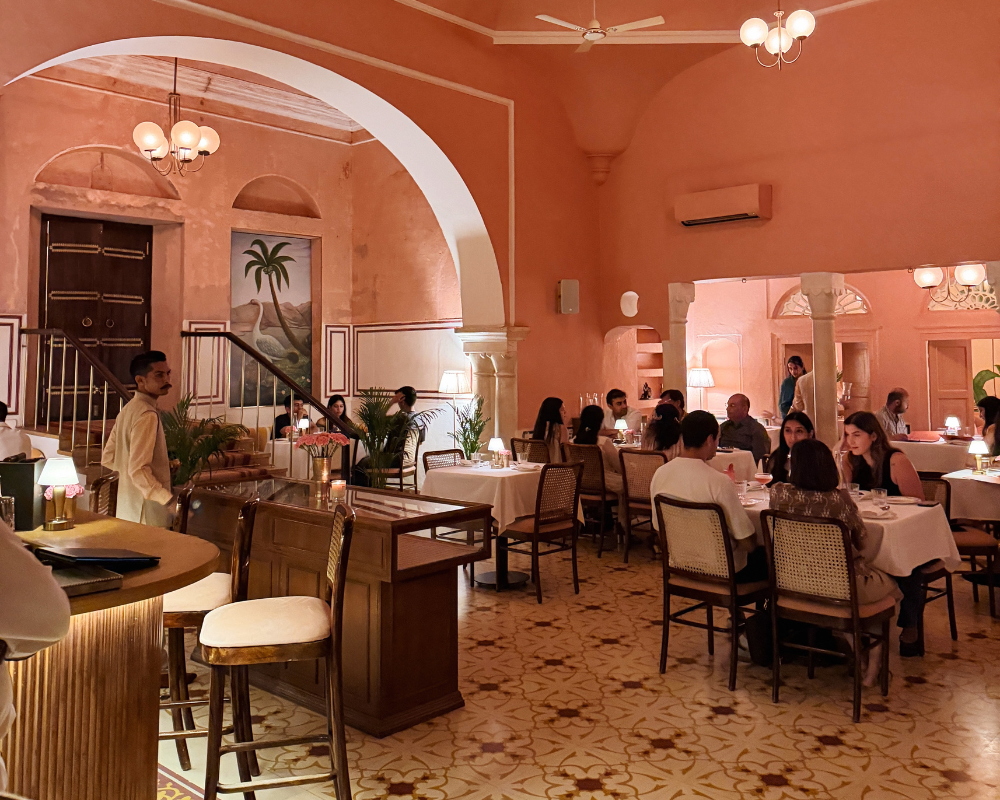  The dusky pink dining room at The Johri Restaurant, Jaipur, with arched doorways and candlelit tables. 