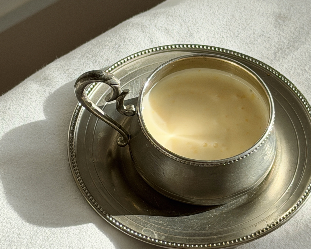  Set Greek yoghurt panna cotta in a vintage silver cup on a white linen surface 