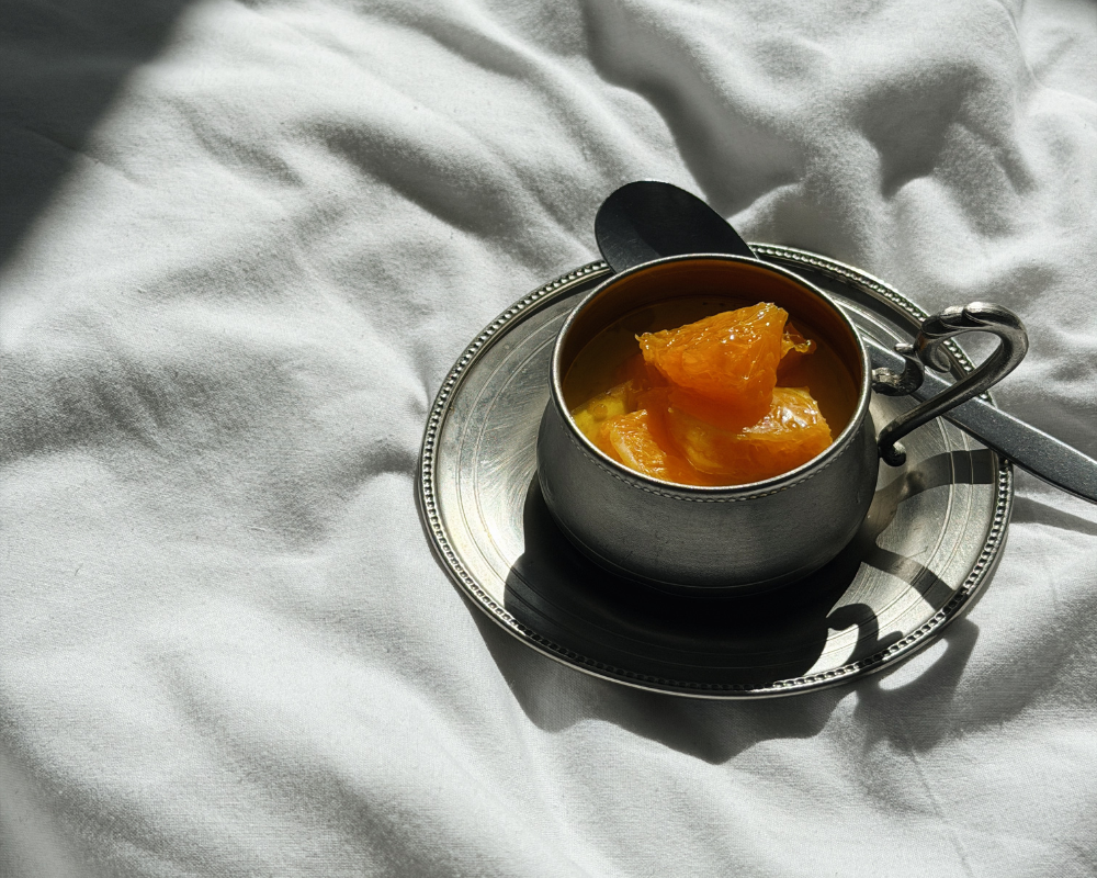  Greek yoghurt panna cotta topped with orange segments in a vintage silver cup on a white linen cloth 
