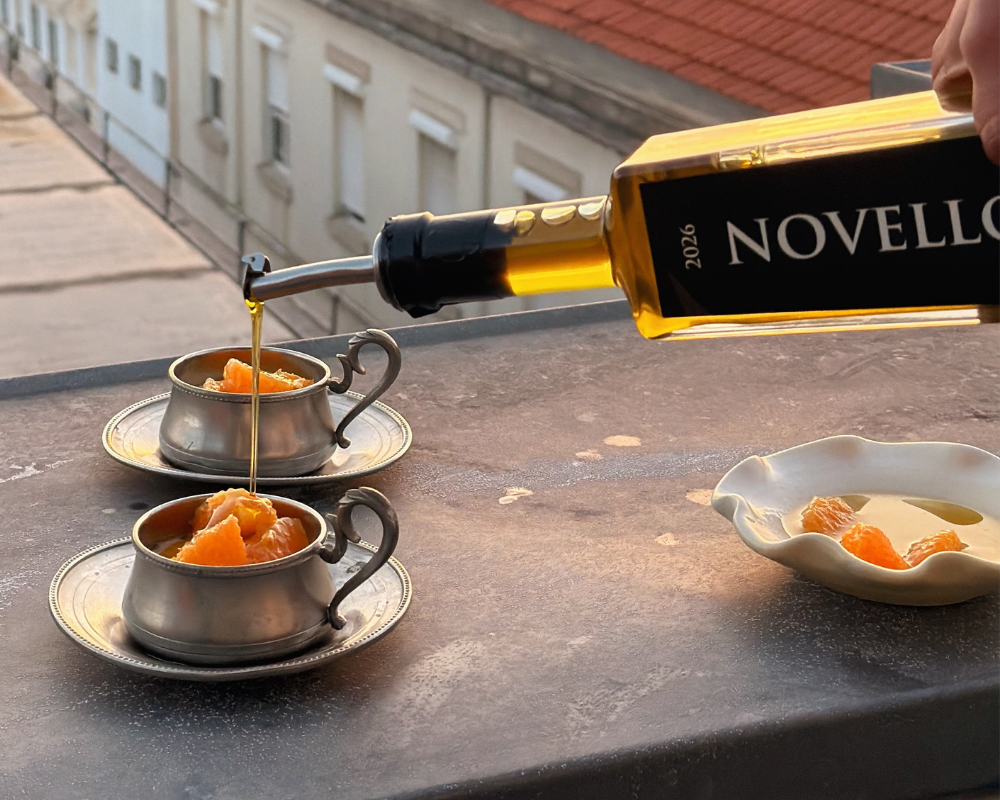  Pouring Pukara Estate Novello extra virgin olive oil over orange panna cotta in vintage silver cups on a rooftop 