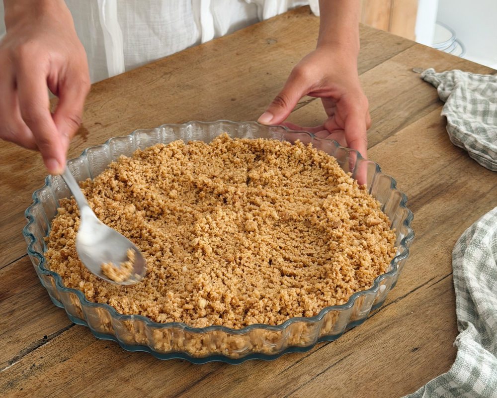  Pressing biscuit crumb base into a fluted tart dish for a no-bake apricot tart 