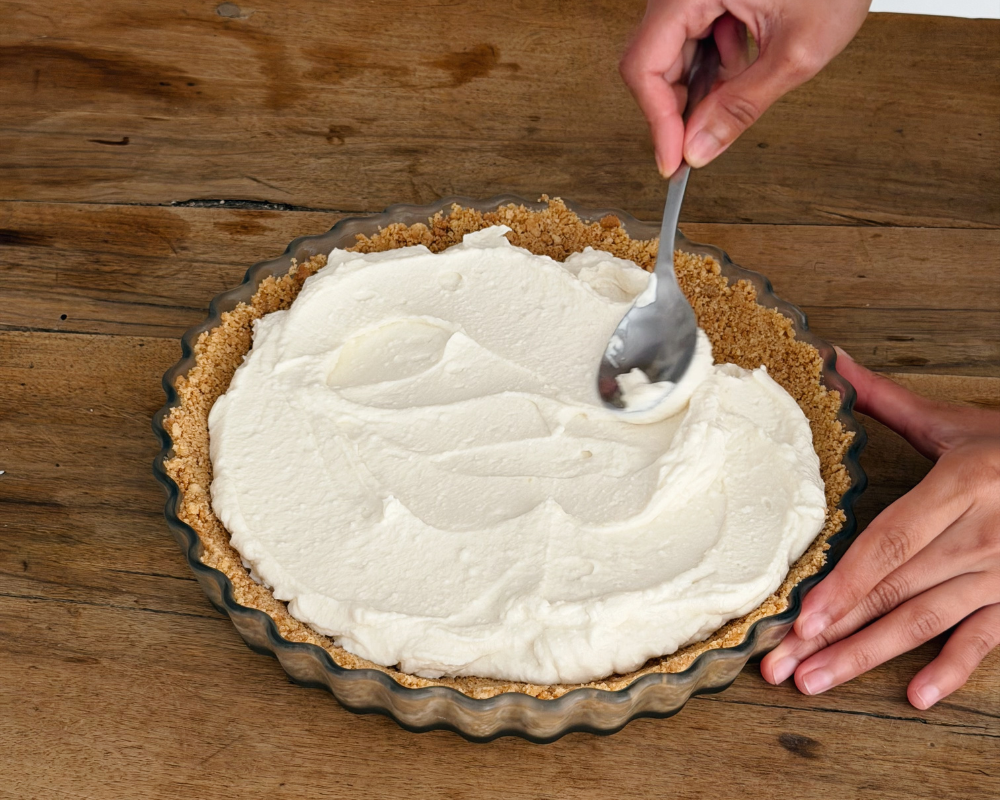  Spreading whipped ricotta and goat's cheese filling into a biscuit crumb tart shell 