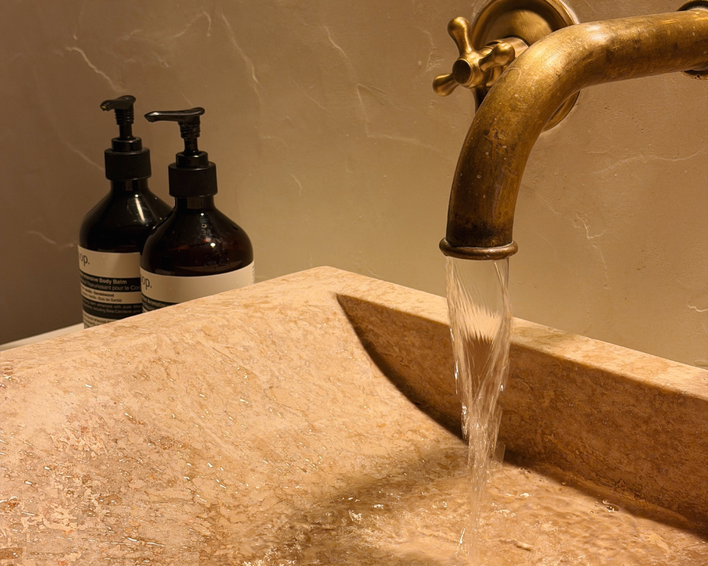  Antique brass tap running water into a hand-carved stone sink at Maison Santcha 