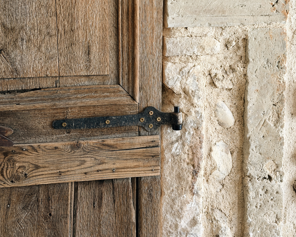  Close-up of an antique wooden door with aged iron hinge at Maison Santcha 
