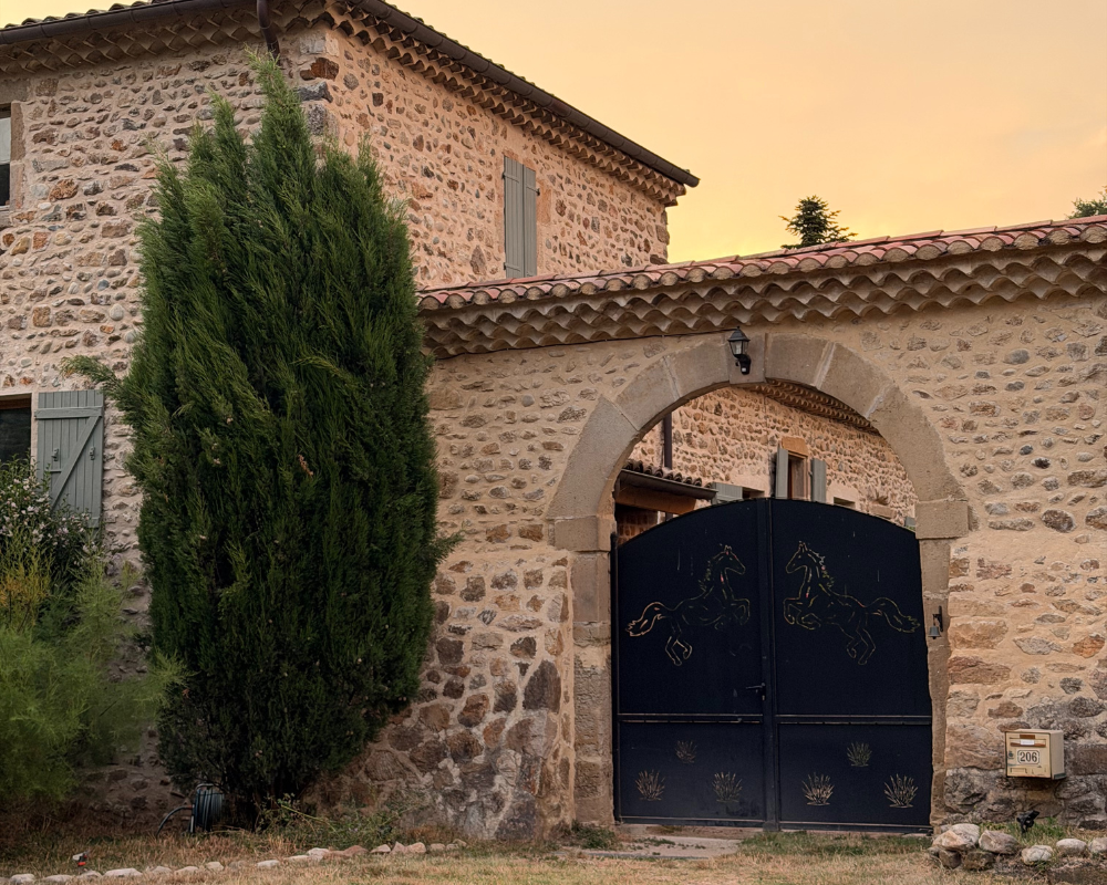  Stone farmhouse exterior with archway gate at sunset, Maison Santcha 
