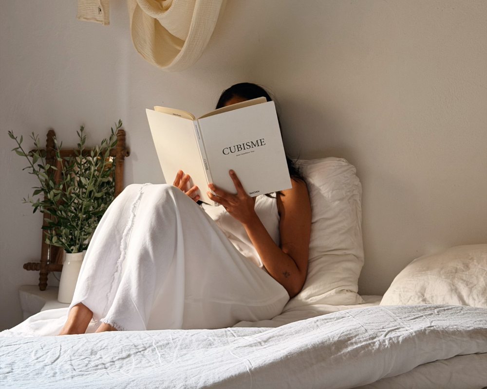  Reading a book on a linen-draped bed at Maison Santcha 