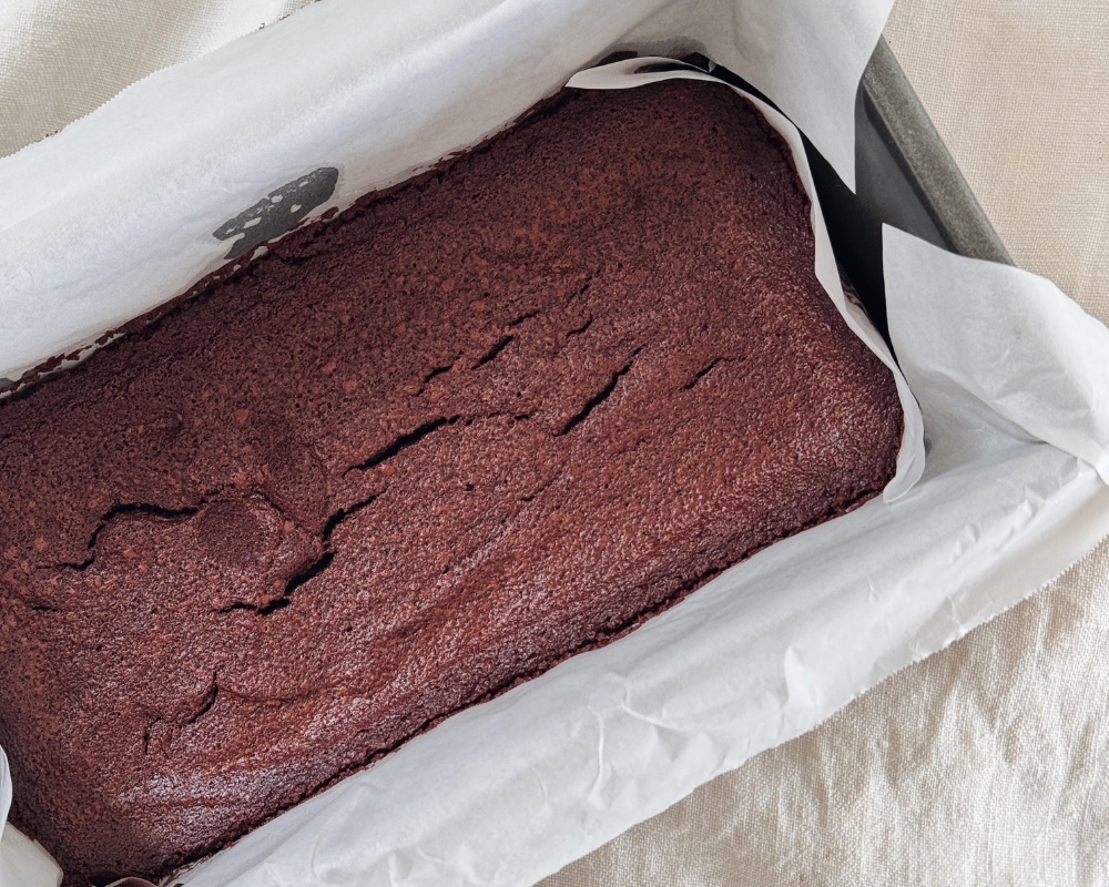  A loaf tin lined with baking paper fresh out of the oven with baked chocolate ganache  