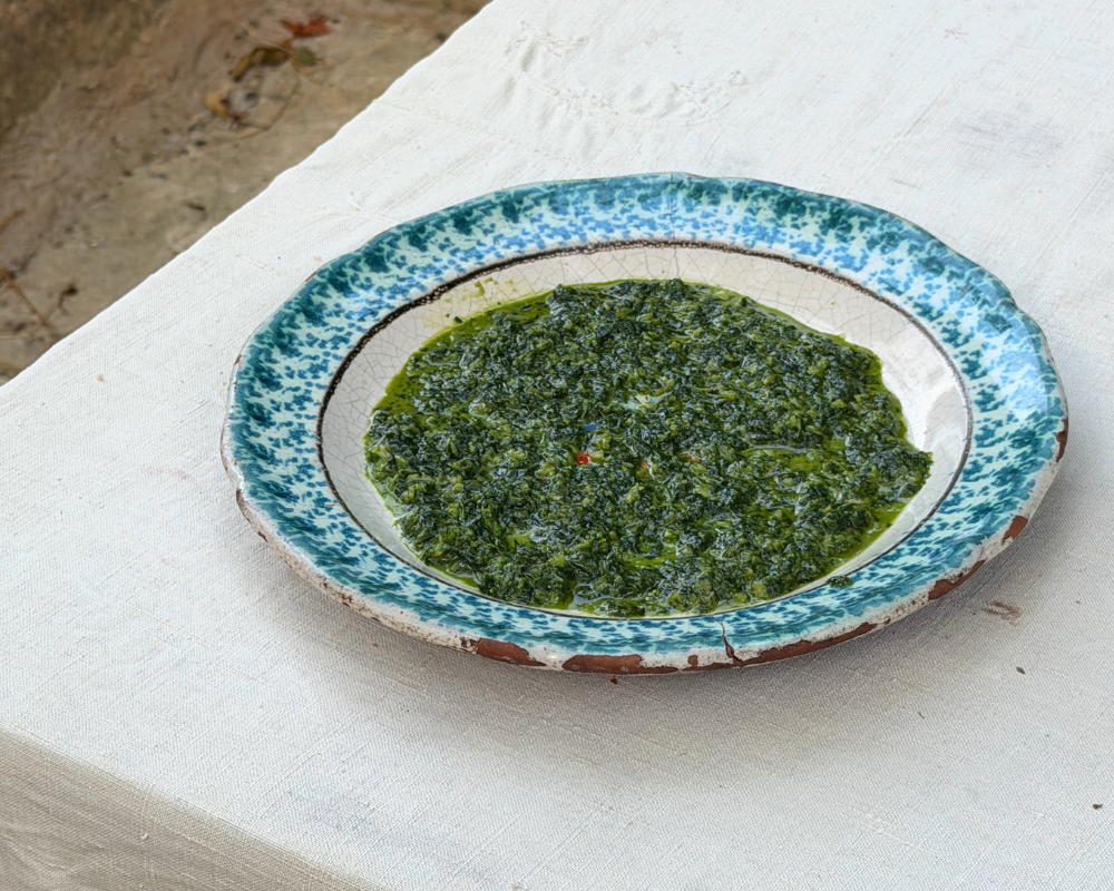  A close-up of fresh green pistou sauce on a ceramic plate. 