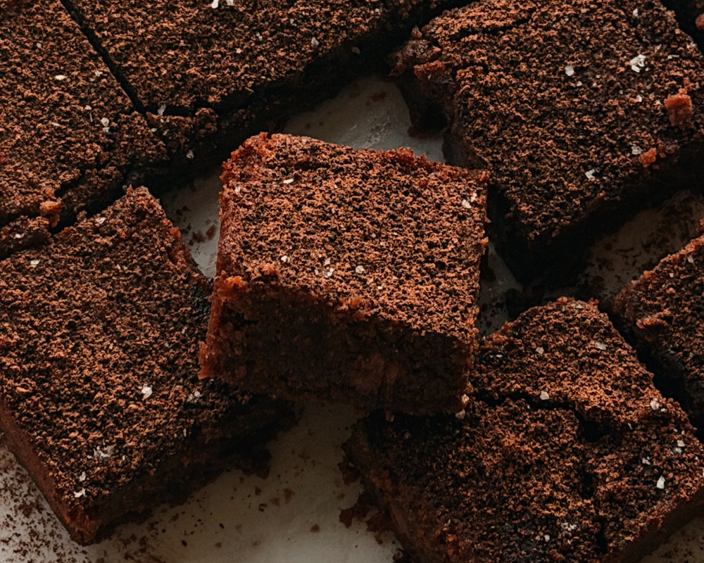  Close up of fudgy hazelnut brownie squares dusted with cocoa powder and sea salt 