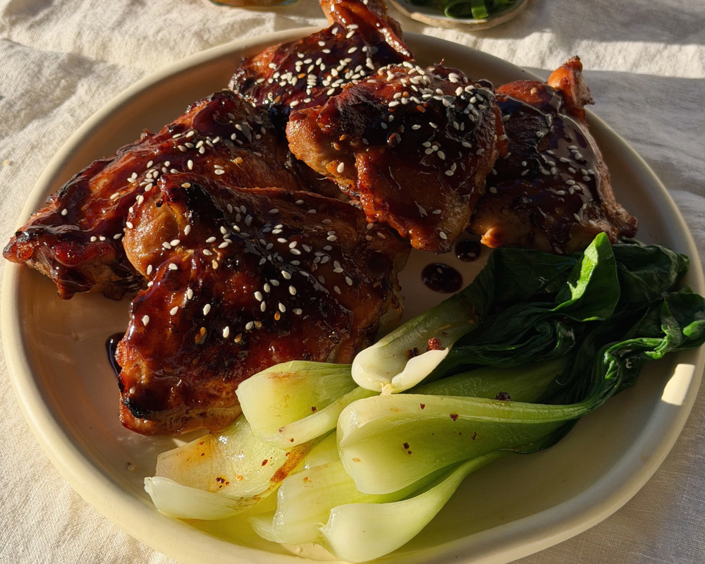  Sticky Miso Honey Chicken. on a plate with steamed bok choy and toasted sesame seeds sprinkled on top. 