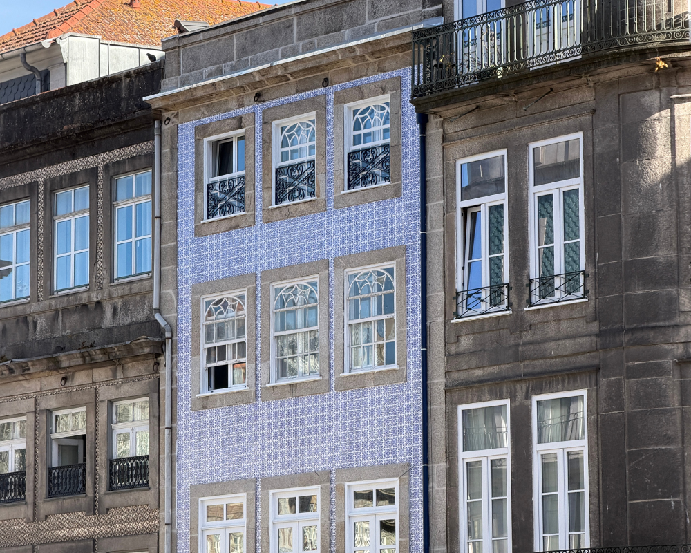  Blue tiled building facade in Porto with black iron balconies 