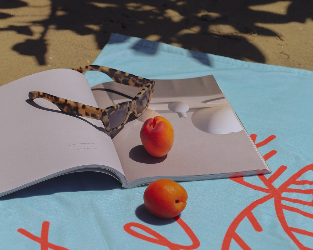 Open magazine with peach and sunglasses, lifestyle editorial content Sydney