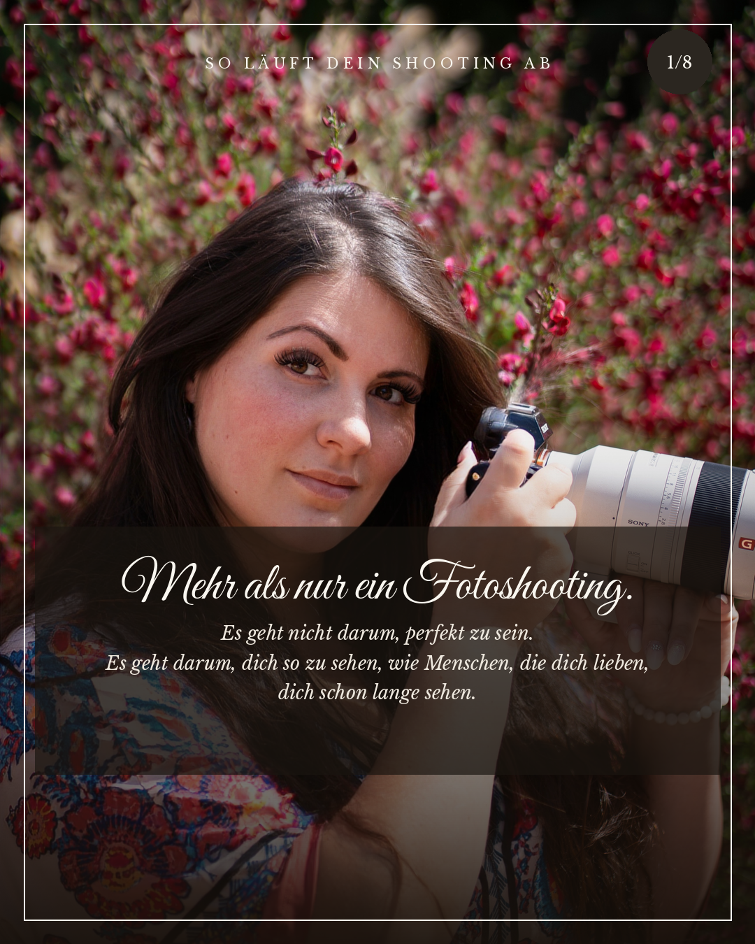 Eine junge Frau mit langen braunen Haaren, die eine Kamera hält und in die Kamera schaut, vor einem Hintergrund voller pinker Blumen.