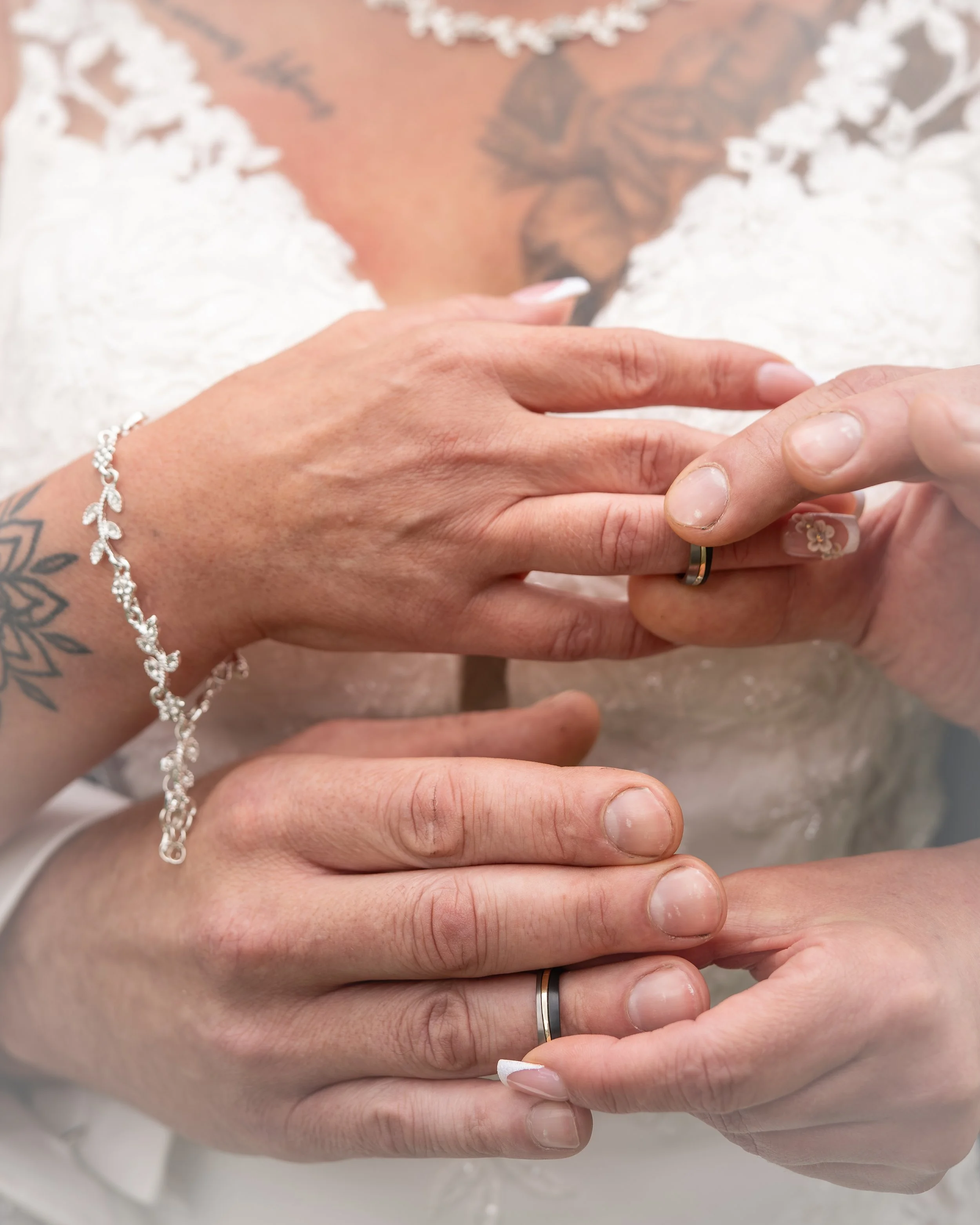 Nahaufnahme der Hände eines Brautpaares, die sich während der Trauung halten, mit Ehering und Brautschmuck sichtbar