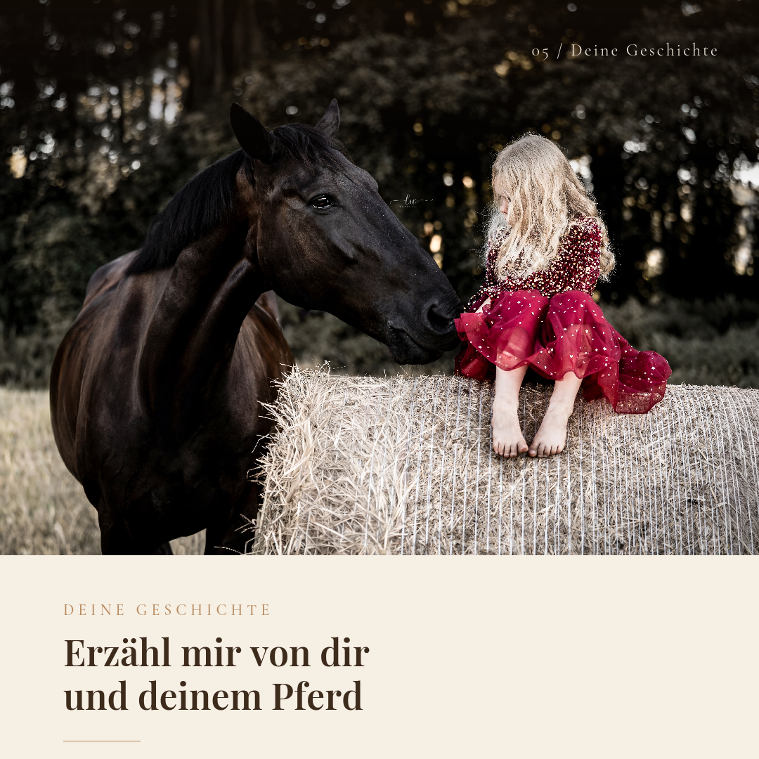Ein kleines Mädchen in einem roten Kleid sitzt nackt auf einem Heuballen, während ein schwarzes Pferd sie sanft beschnuppert, umgeben von einer natürlichen Waldhelligkeit im Hintergrund.