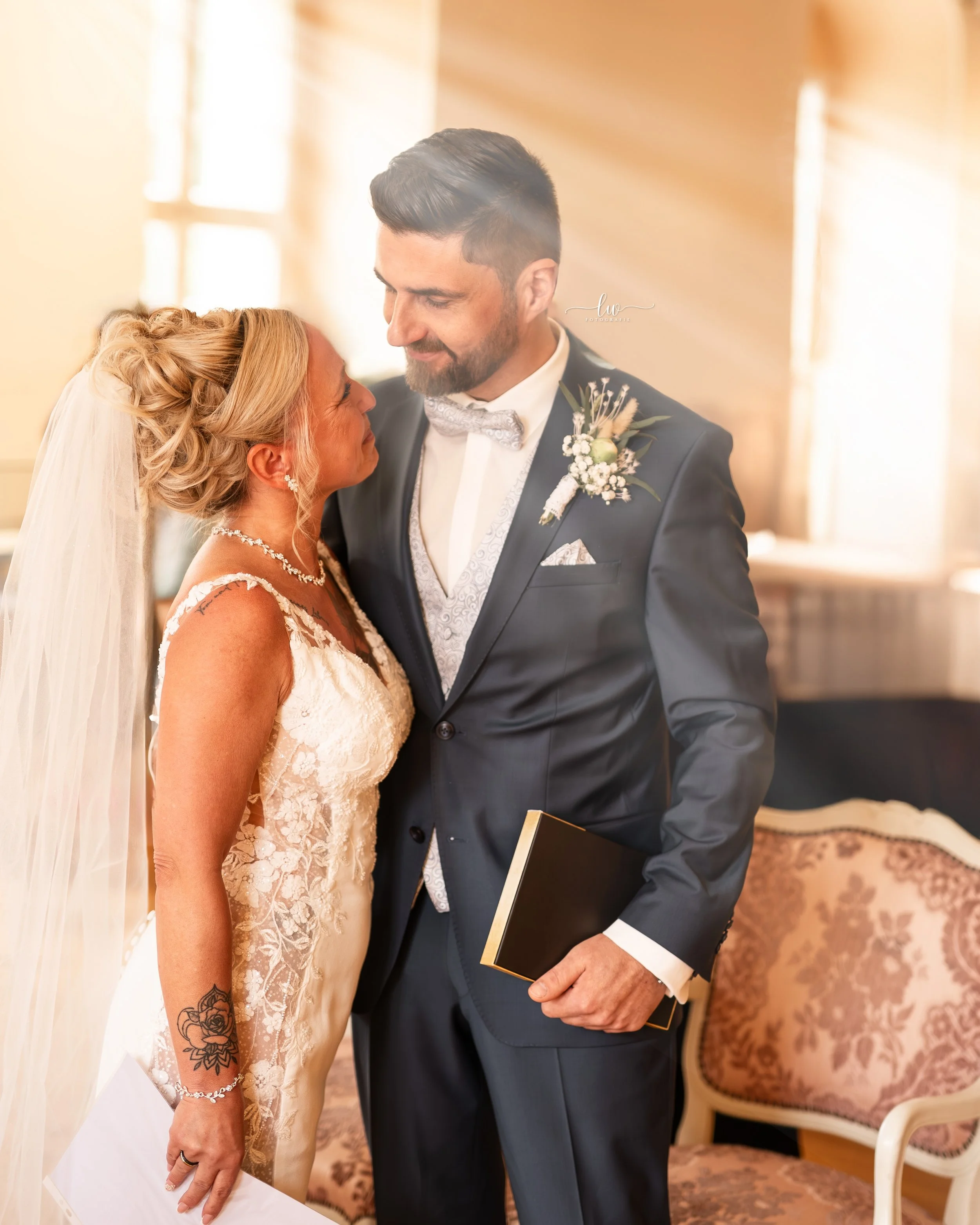 Ein Brautpaar beim Heiratsritual, das sich in die Augen schaut, bei einer Hochzeit in einem Raum mit warmem Licht und antiken Möbeln.