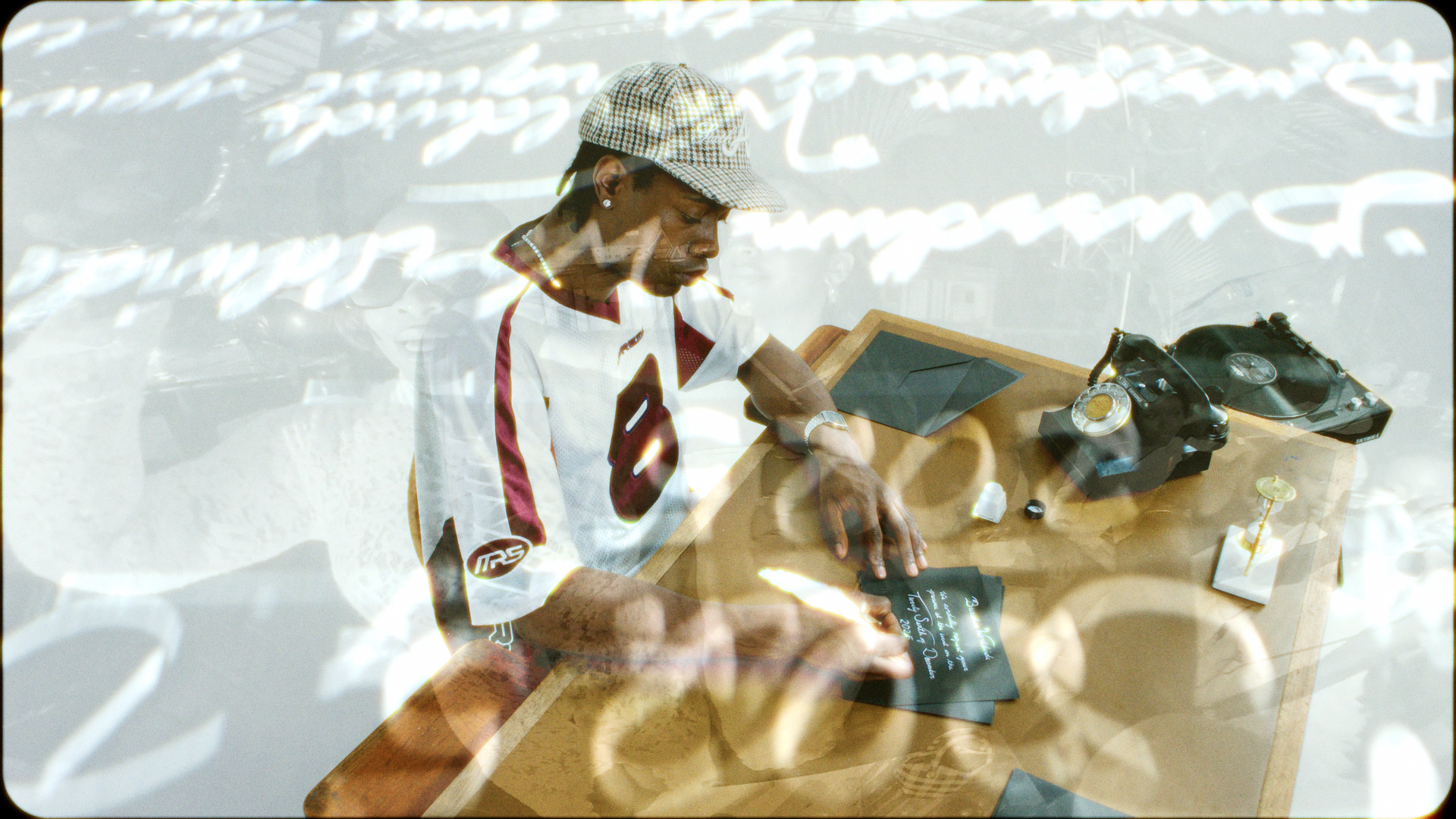 A young man wearing a baseball cap and sports jersey is standing at a wooden table with electronic devices, including a vintage rotary phone and a landline telephone. The scene has a double exposure or reflective overlay with white text or patterns.