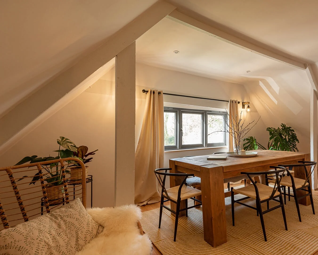 Farmhouse table and chairs by a window with plants and cosy chairs at the snug room at Melancoose