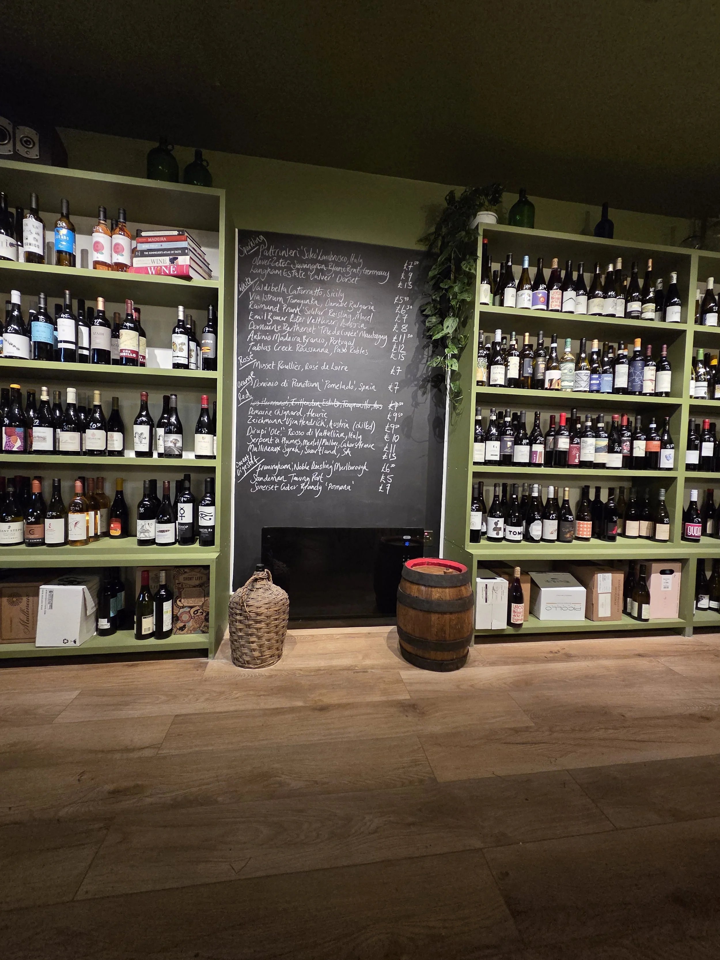 Shelves filled with wine bottles and a chalkboard menu in a wine shop or bar.