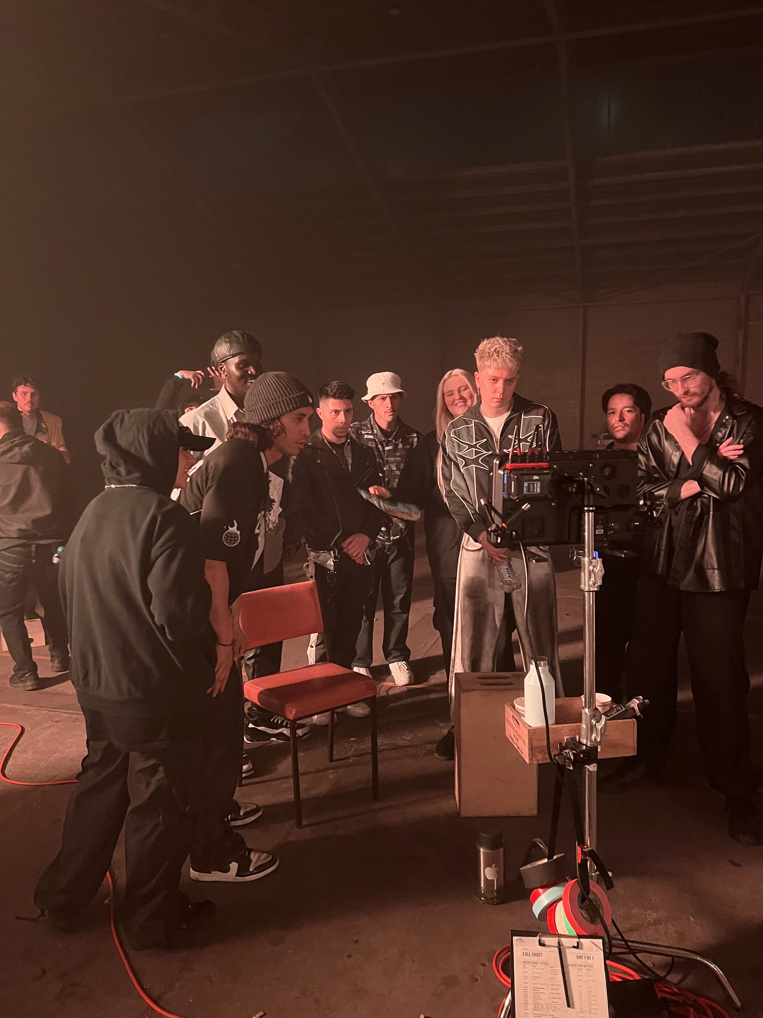 A group of people gathered around a monitor on a film set.