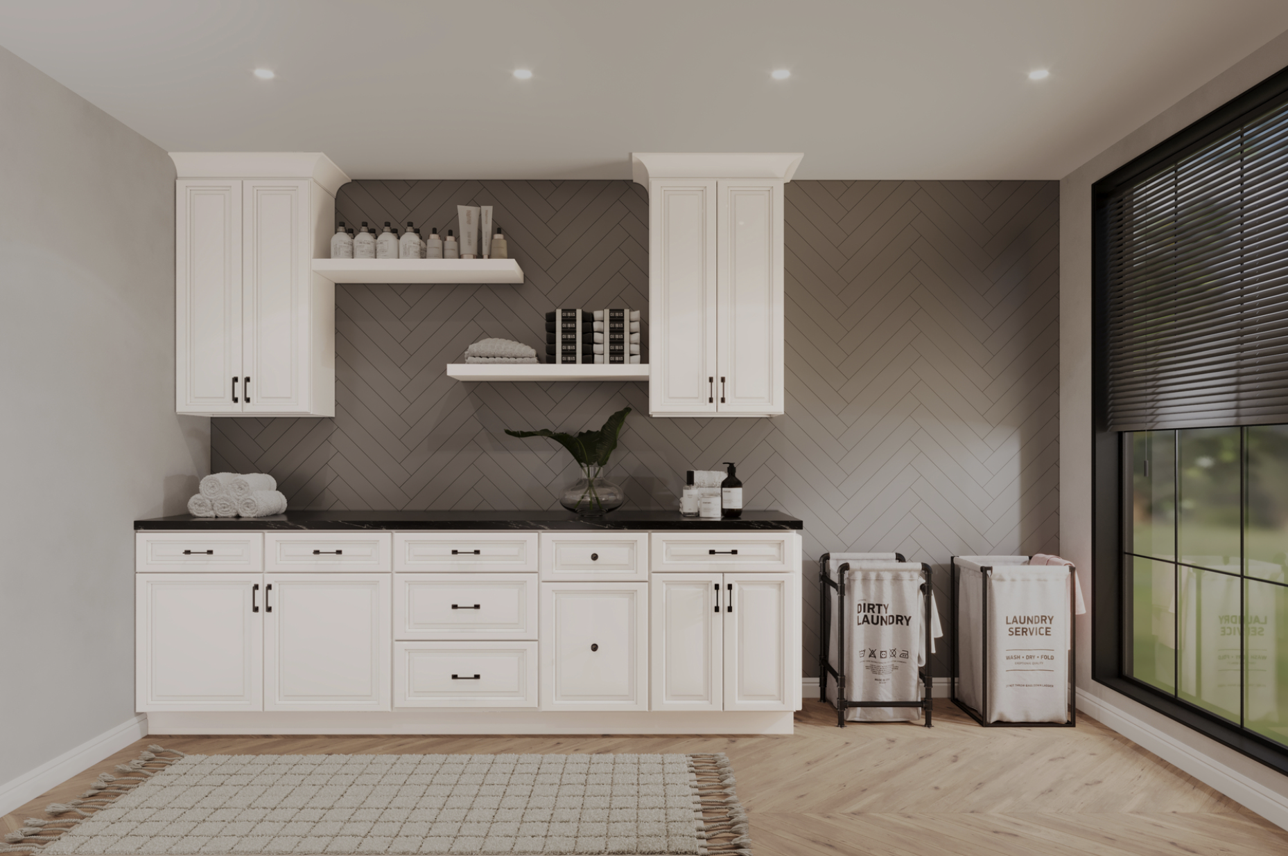 Laundry room with white cabinets, black countertop, beige herringbone accent wall, large window with blinds, laundry baskets, folded towels, plant, and laundry products.