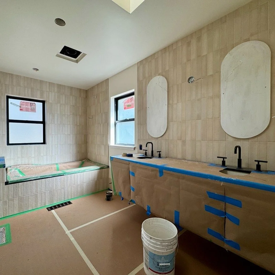 A bathroom under construction, floors and cabinets are covered in protective paper.
