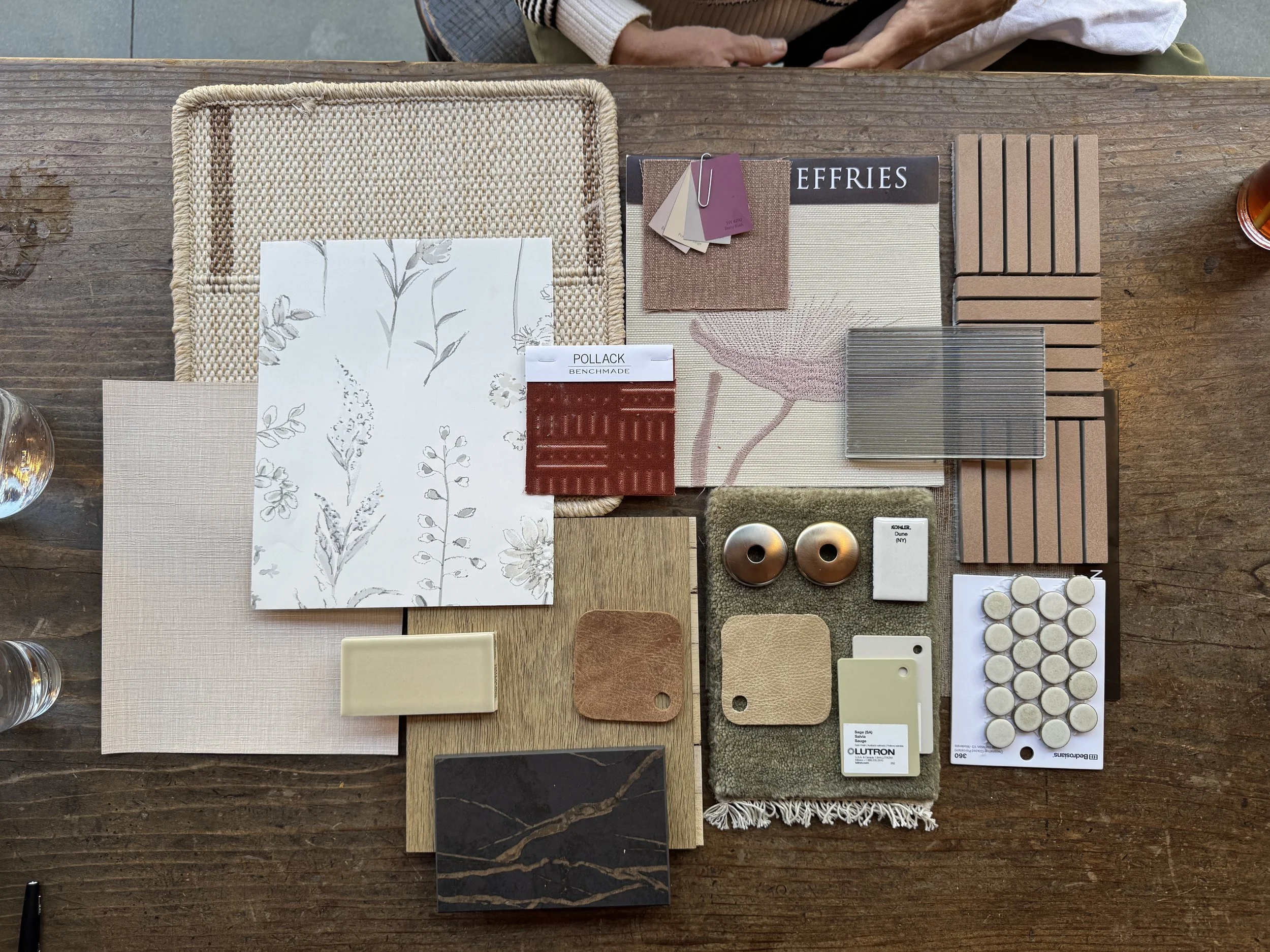 Various samples of tile, metals, wallpapers, glass, etc laid out on a table.