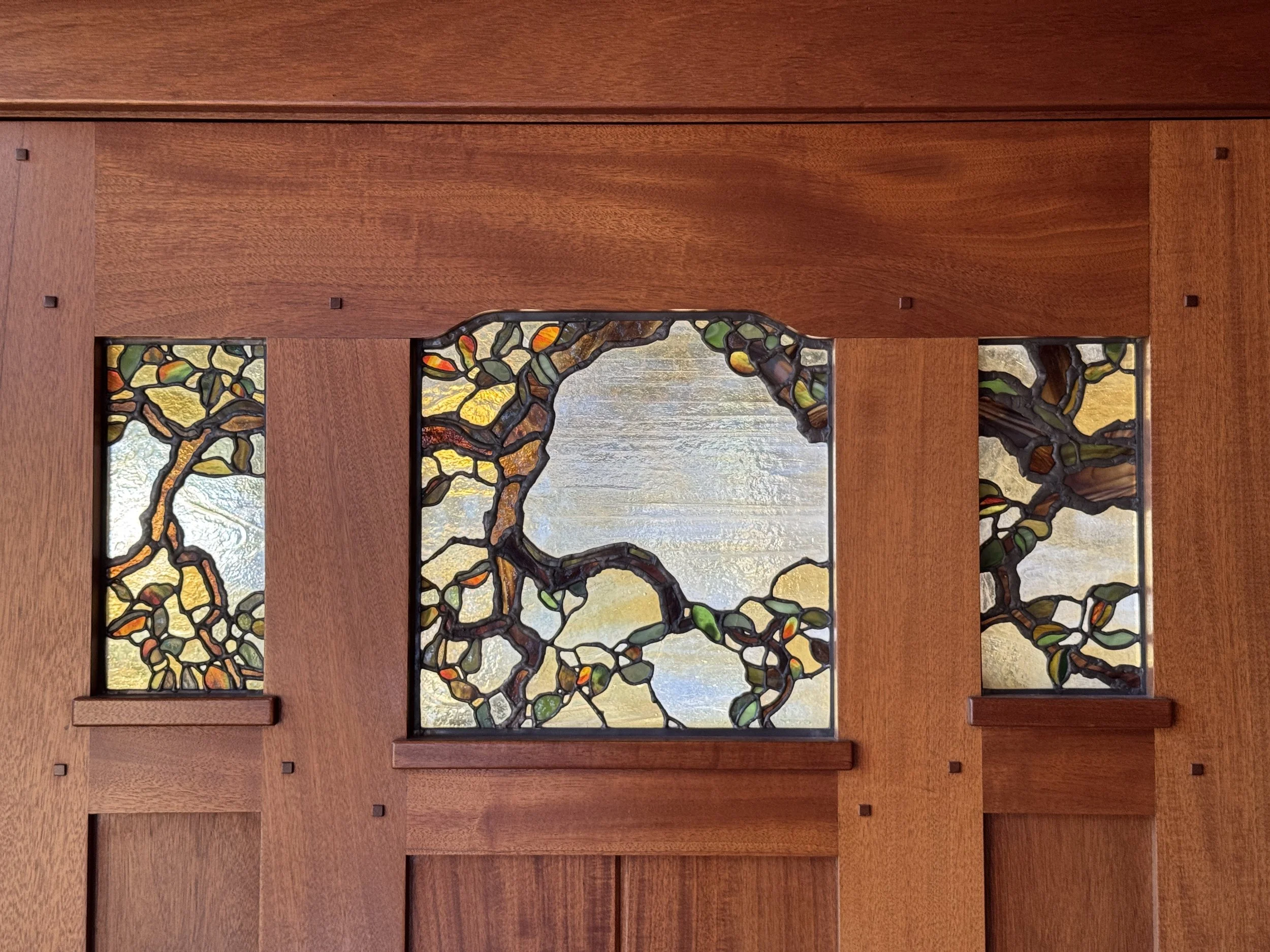 Stained glass of a tree set into a wooden door.