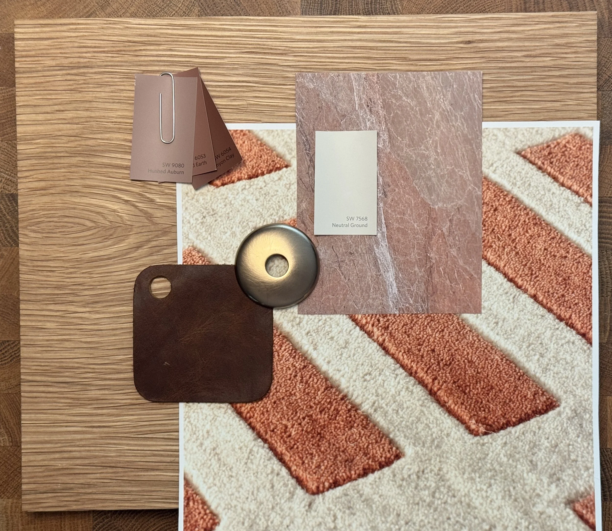 Material samples in oak, deep brown leather and brass.