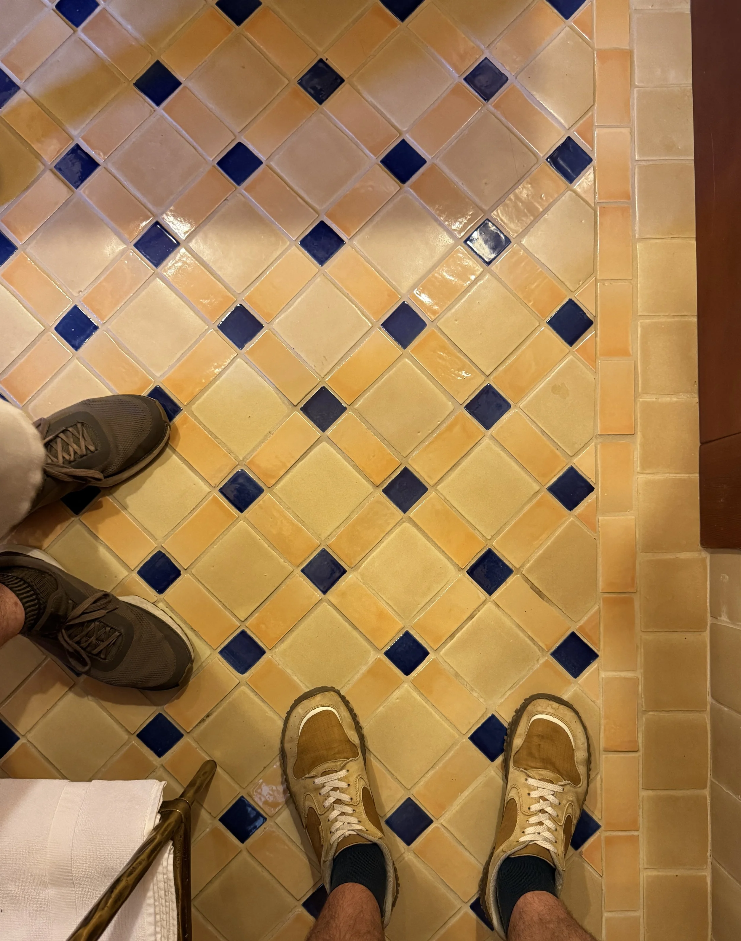 A tiles bathroom floor in yellows and navy blue.