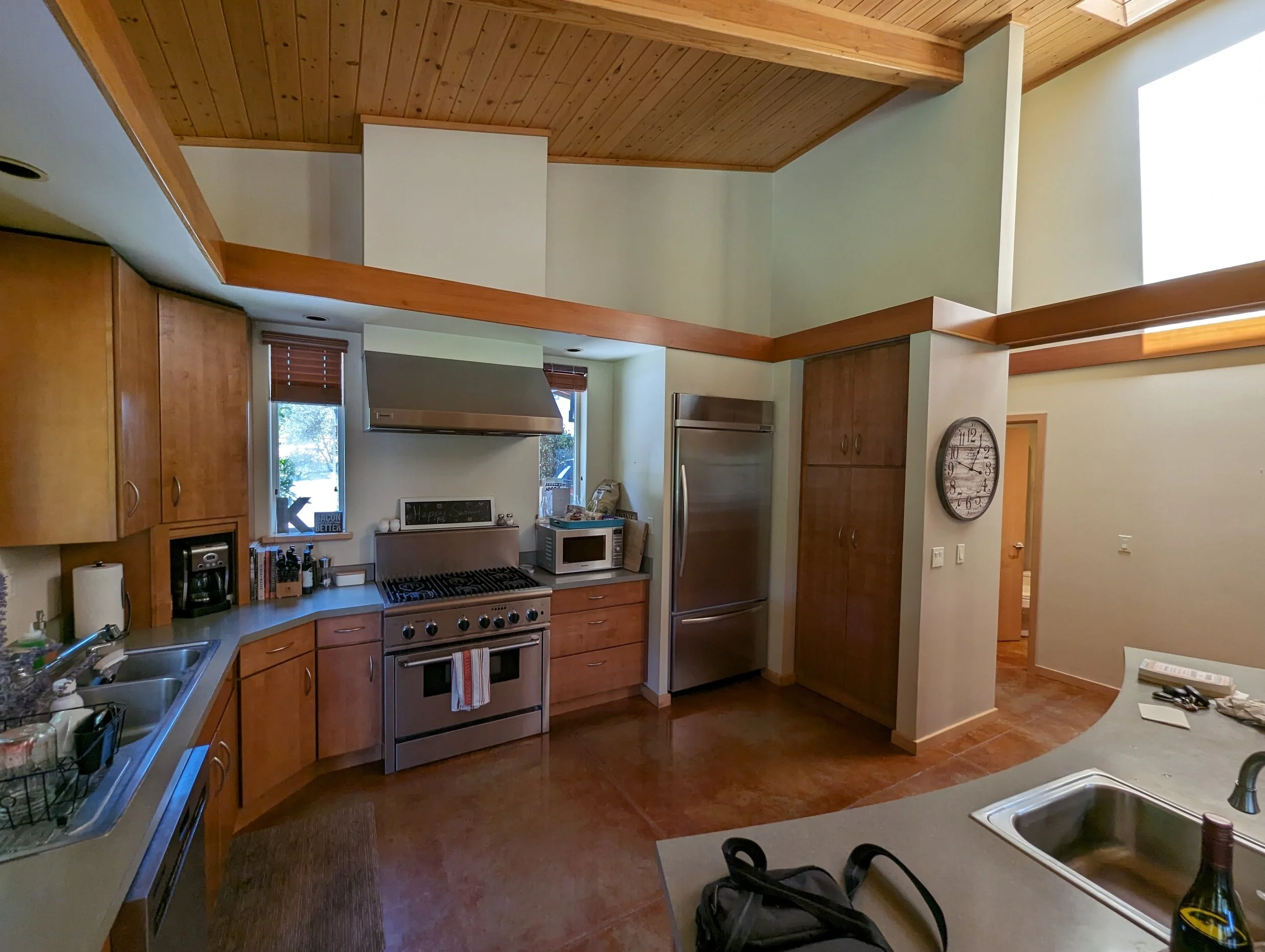 The existing kitchen with orange-stained concrete floors and dark cherry cabinetry.