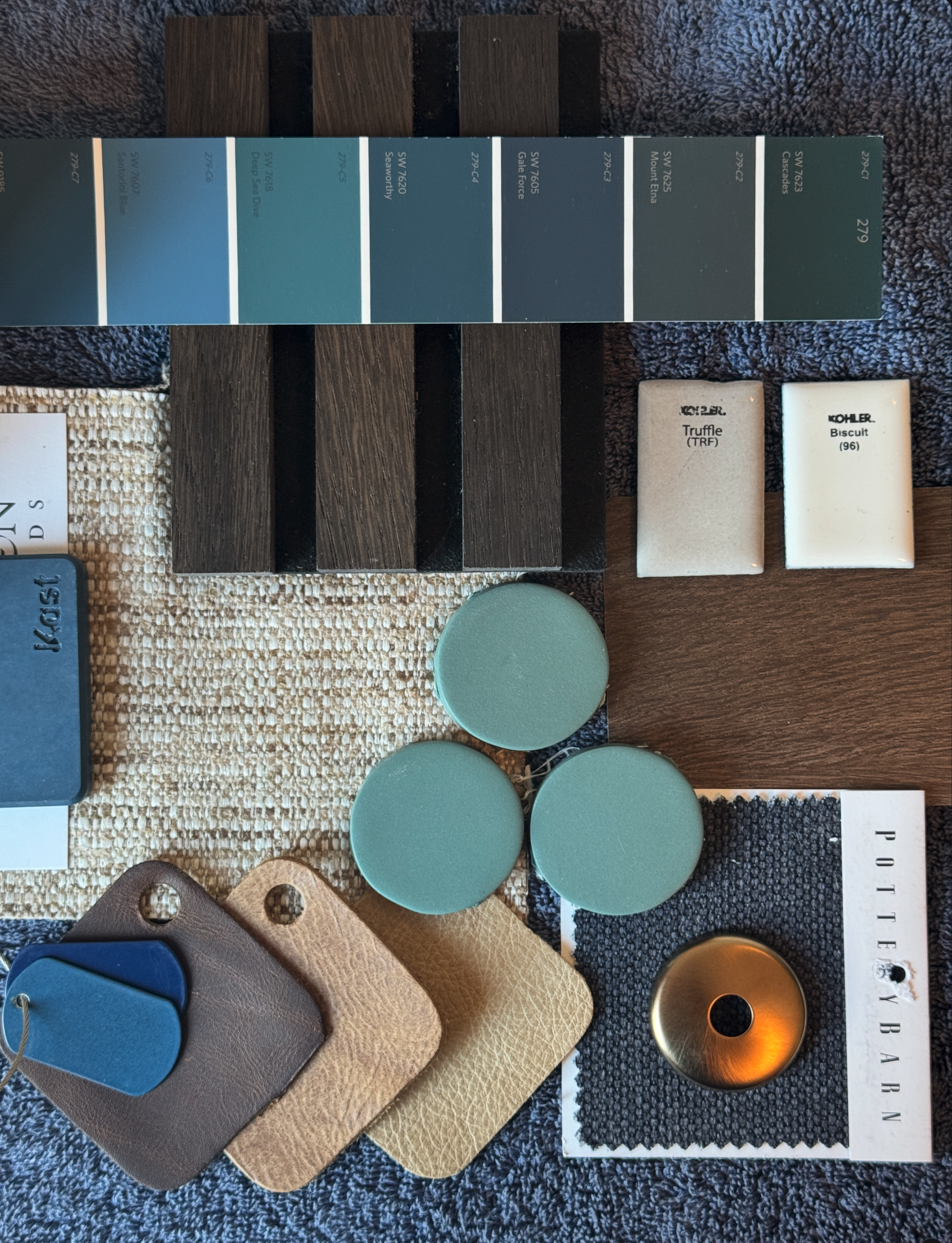 Samples of tile, stone, fabrics, metals an paint colors in a dark, masculine palette