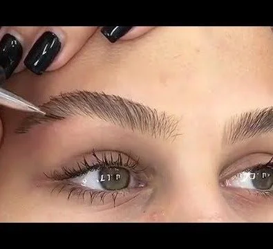 Close-up of a person having their eyebrows shaped or tinted by a beauty professional.