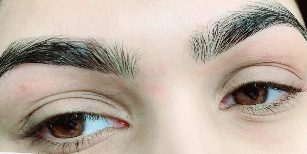 Close-up of a person's eyes with groomed eyebrows and natural makeup.