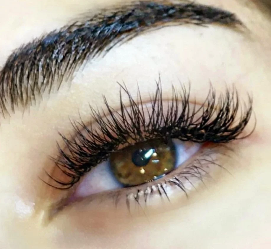 Close-up of an eye with brown iris, long eyelashes, and well-groomed eyebrow.