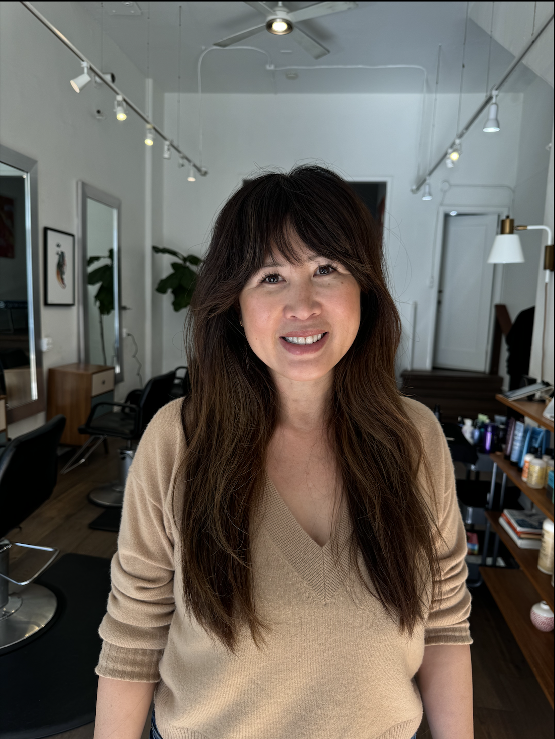 Woman smiling with hair salon in background