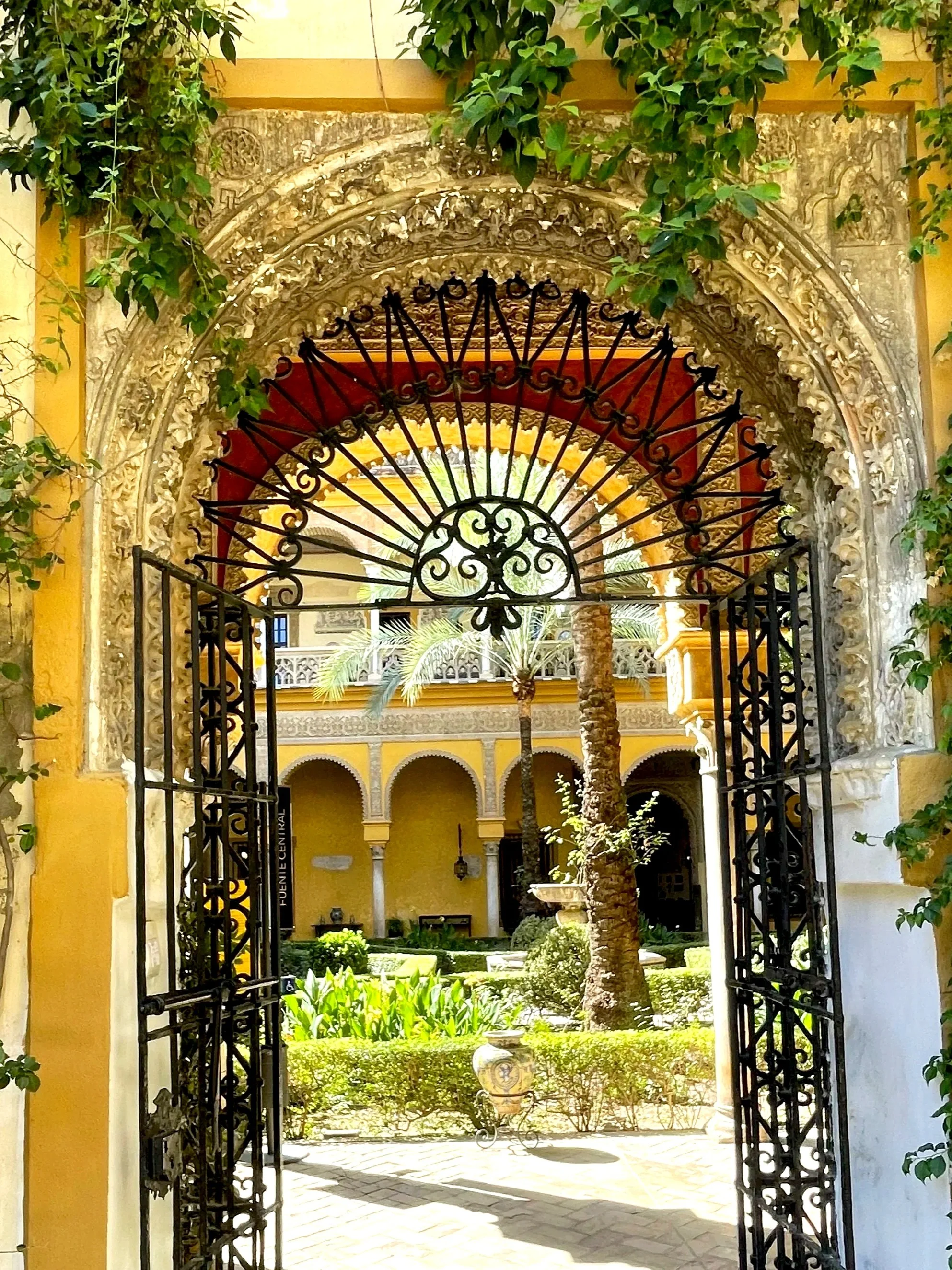 Andalusian courtyard and garden seen through an ornate gateway, Ishbiliya-Seville.